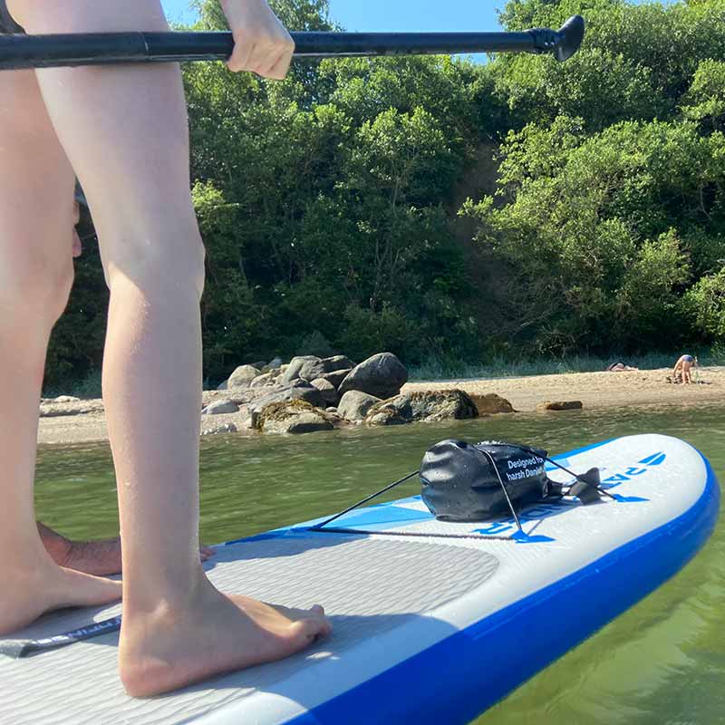 Vandtæt taske Dry Bag Rygsæk™ fra danske Owlbite® på 10L (Liter), sort. Set på paddleboard i vand.