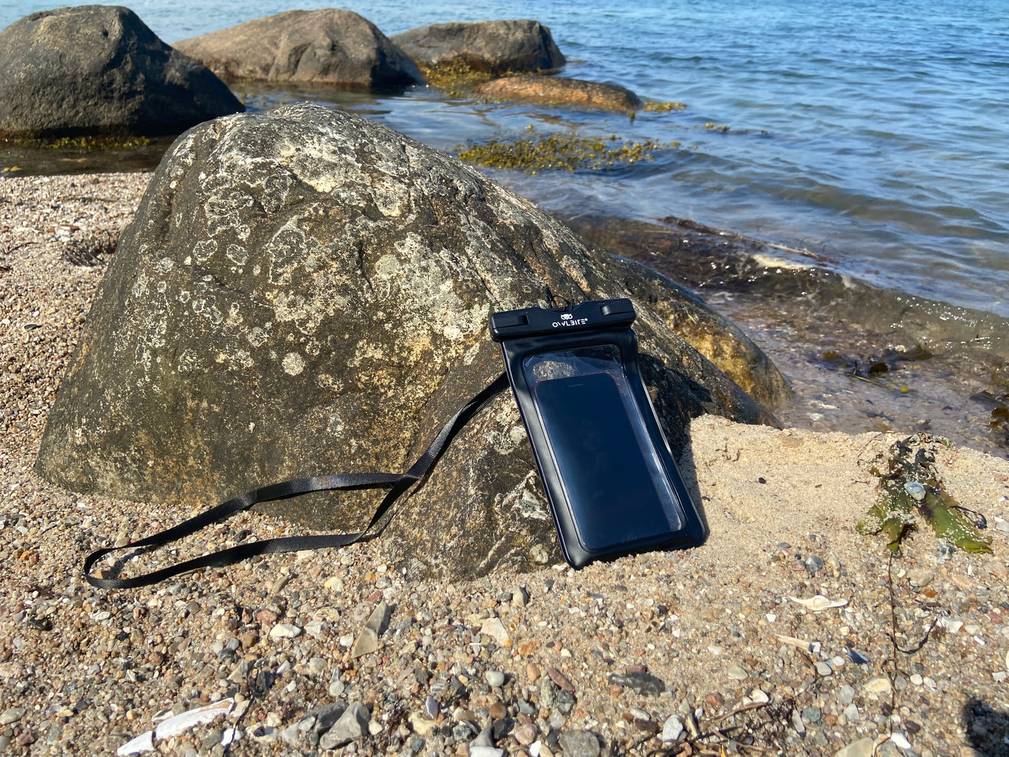 Vandtæt pose til mobil: Overborde Mobilpose™ Telefon-etui fra Owlbite®. Set på stranden.